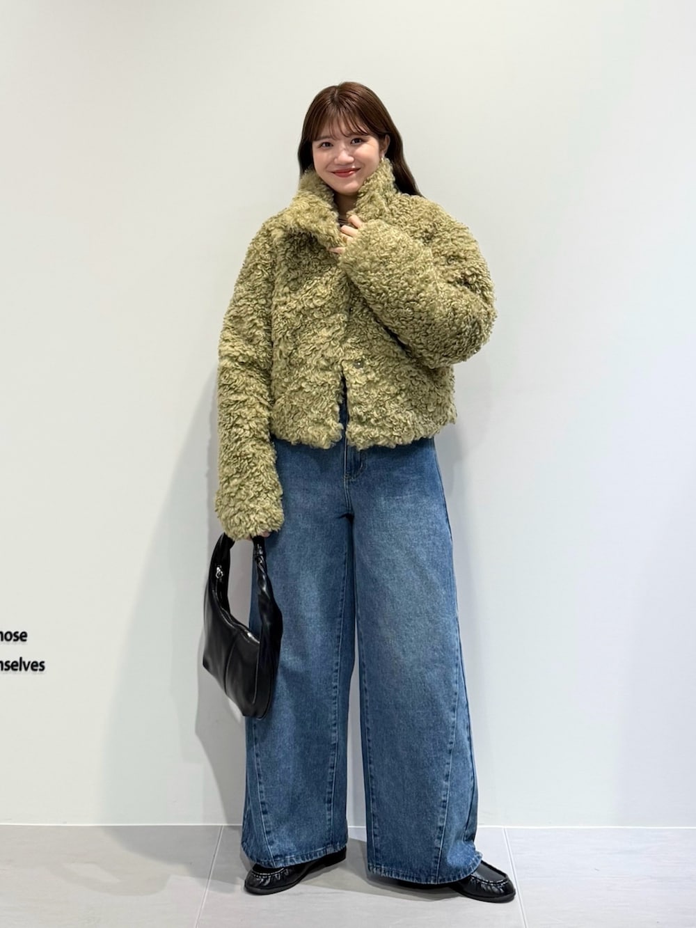 グリーン系のその他アウター、ブルー系のデニムパンツ、ブラック系のハンドバッグを着用したレディースの秋コーディネートの5枚目の写真