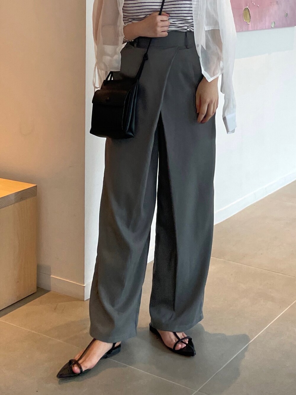 グレー系のスラックス、ホワイト系のサンダル、ブラック系のショルダーバッグを着用したレディースの夏コーディネートの3枚目の写真