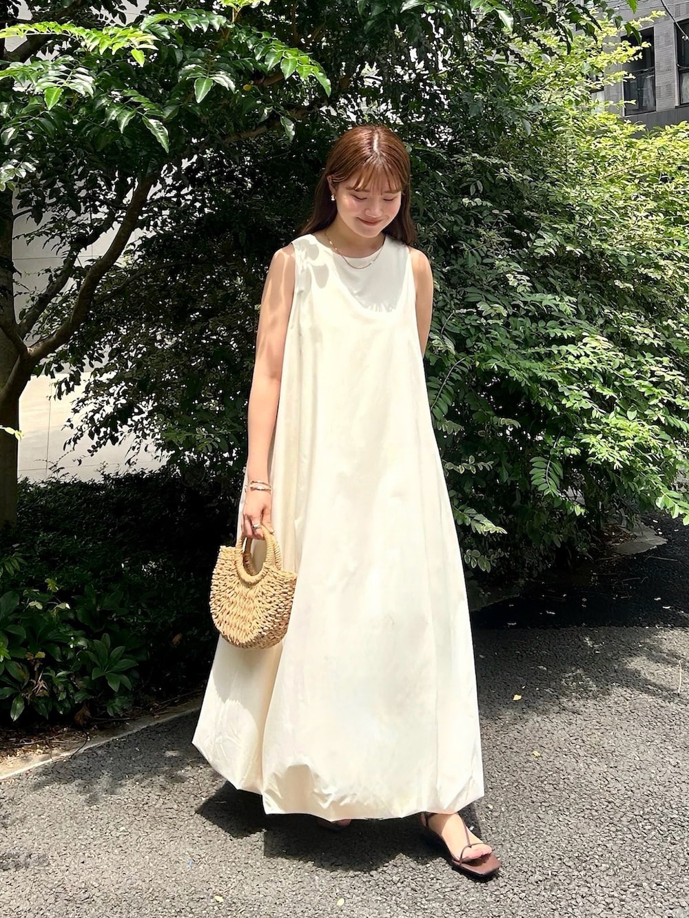 ホワイト系のワンピース、ホワイト系のサンダル、ベージュ系のかごバッグを着用したレディースの夏コーディネートの2枚目の写真