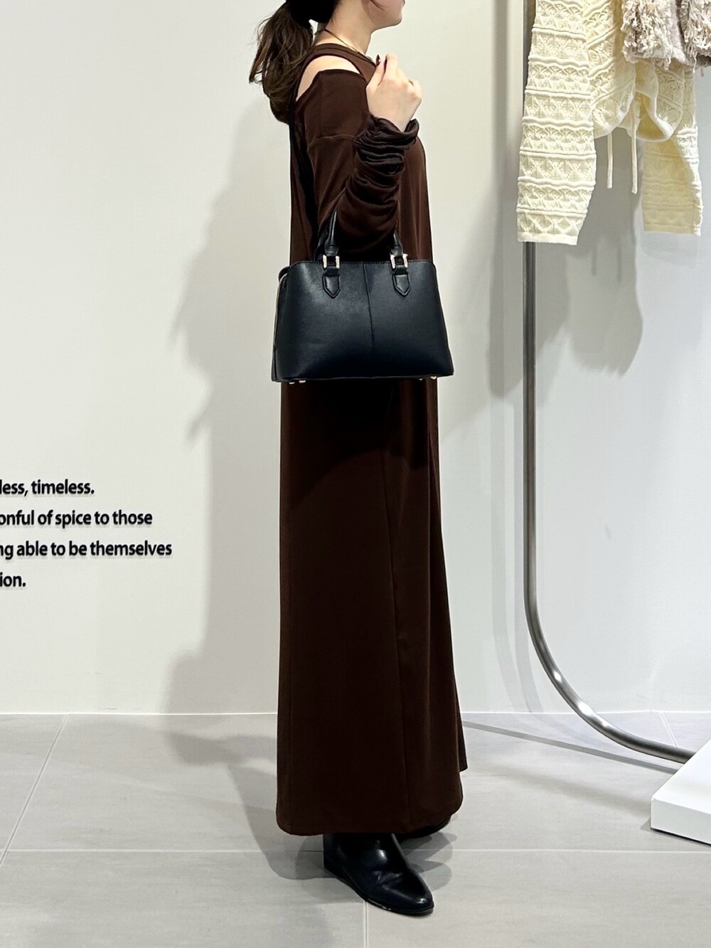 ブラック系のハンドバッグ、ブラウン系のワンピースを着用したレディースの秋コーディネートの3枚目の写真