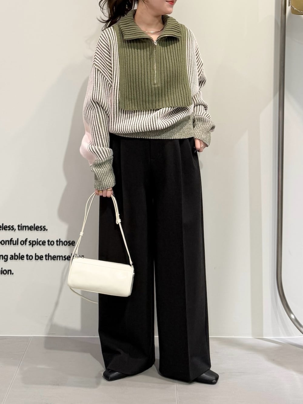 グリーン系のニット/セーター、ブラック系のその他パンツ、ホワイト系のショルダーバッグを着用したレディースの冬コーディネートの2枚目の写真