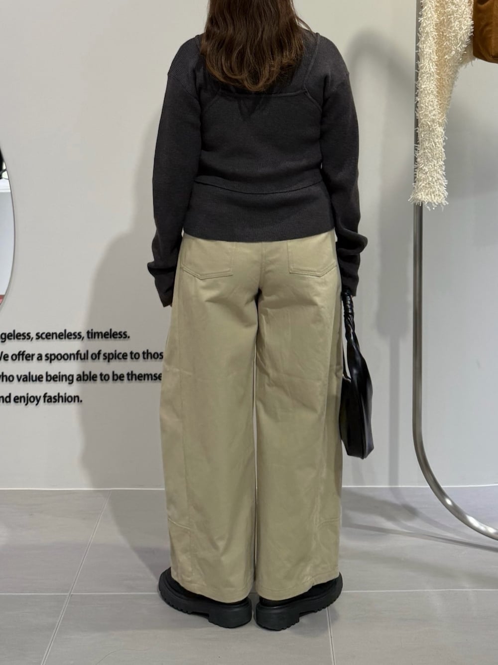 グレー系のニット/セーター、ベージュ系のその他パンツ、ブラック系のハンドバッグを着用したレディースの秋コーディネートの3枚目の写真