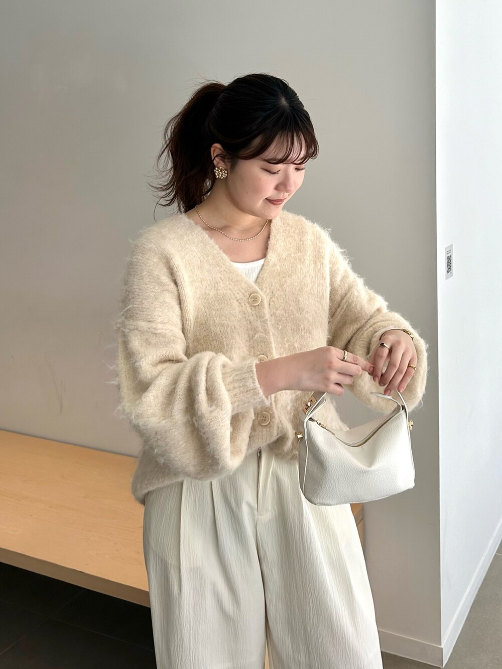 ホワイト系のスラックス、ホワイト系のカーディガン/ボレロ、ブラック系のショルダーバッグを着用したレディースの春コーディネートの2枚目の写真