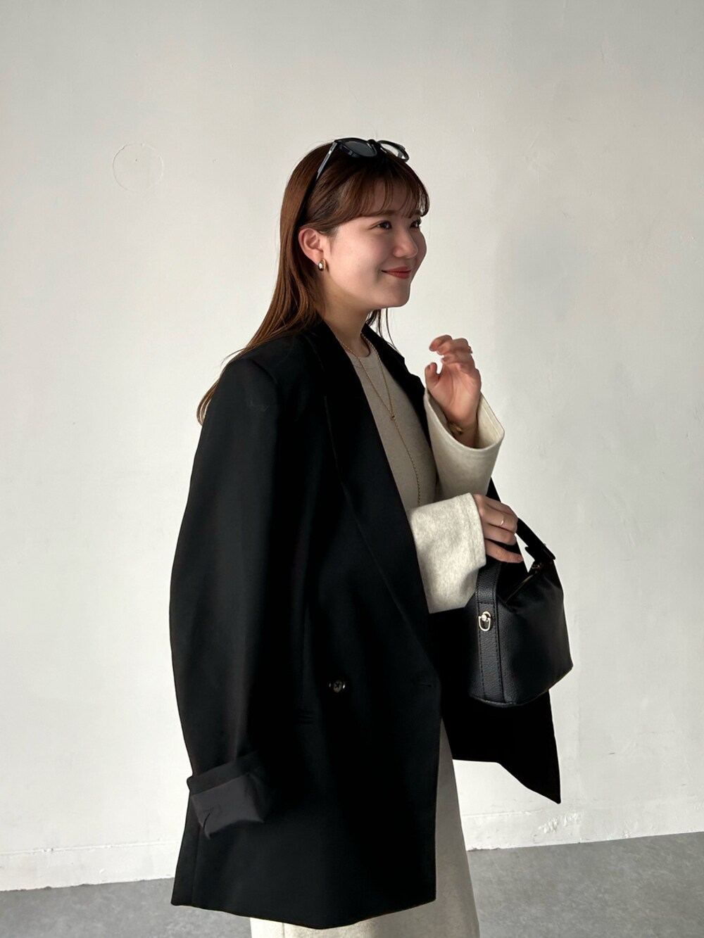 ベージュ系のワンピース、ブラック系のジャケット/アウター、ブラック系のショルダーバッグを着用したレディースの春コーディネートの3枚目の写真