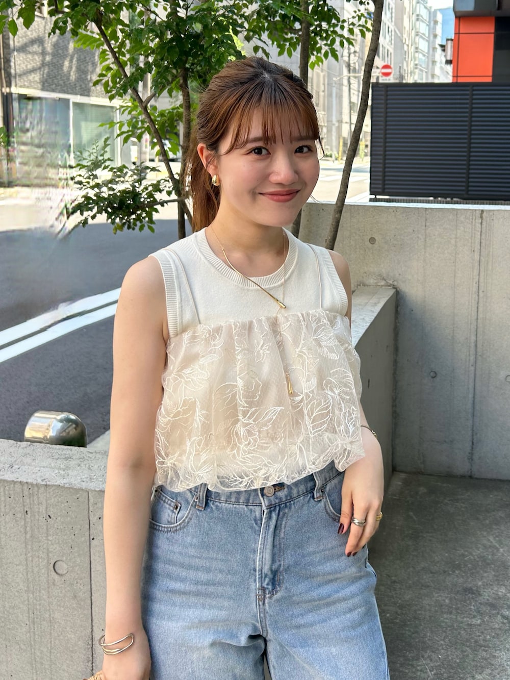 ベージュ系のキャミソール、ブルー系のデニムパンツ、ホワイト系のサンダルを着用したレディースの夏コーディネートの2枚目の写真