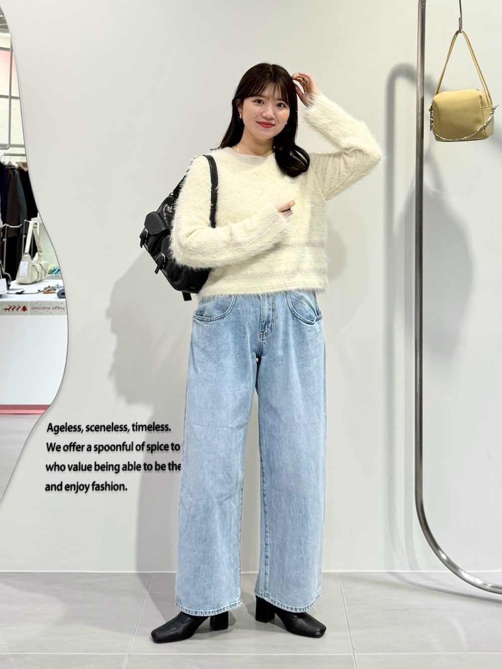 ホワイト系のニット/セーター、ブルー系のデニムパンツ、ブラウン系のショルダーバッグを着用したレディースの冬コーディネートの2枚目の写真