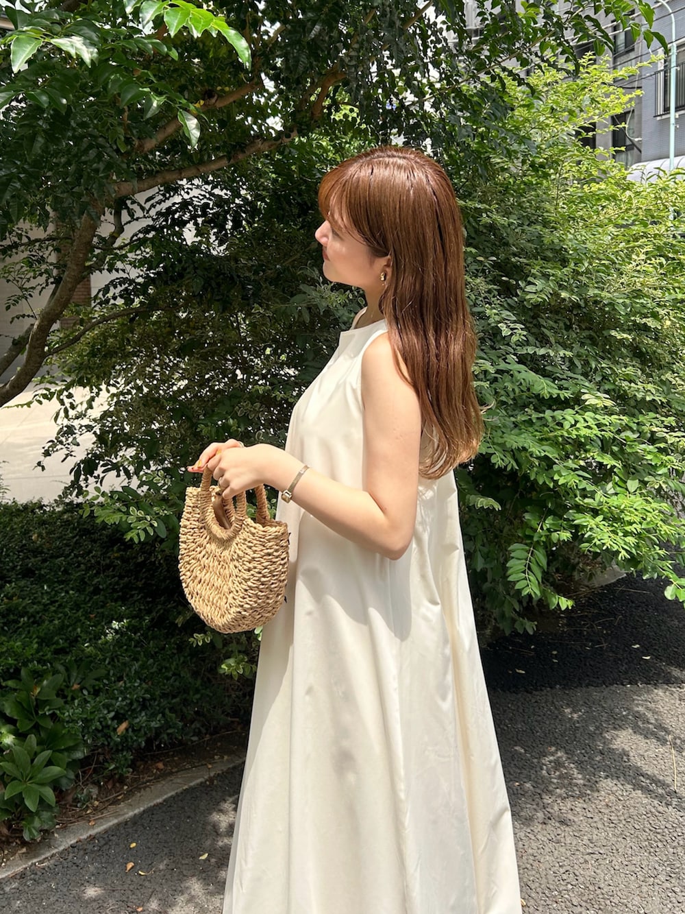 ホワイト系のワンピース、ホワイト系のサンダル、ベージュ系のかごバッグを着用したレディースの夏コーディネートの3枚目の写真