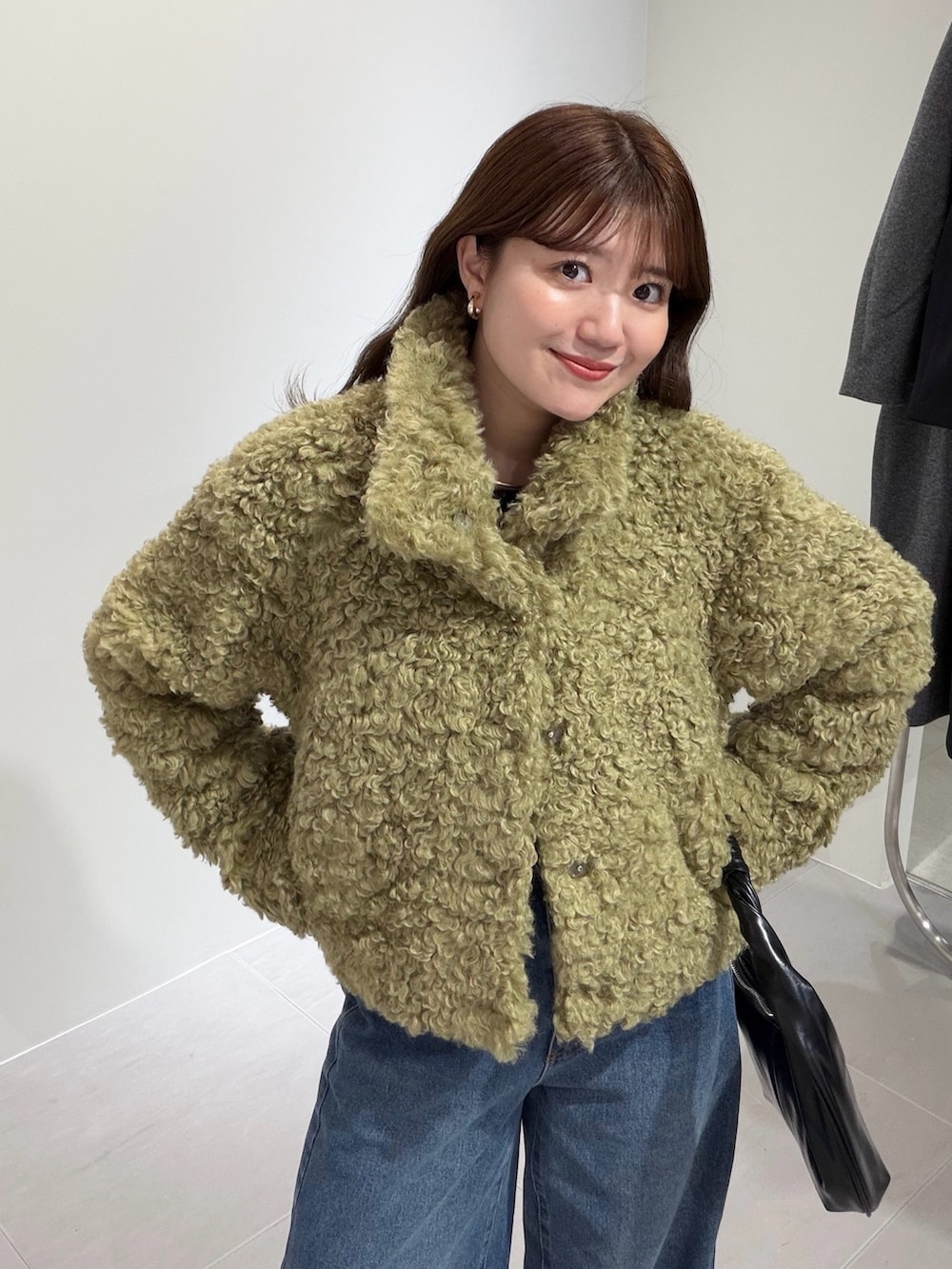 グリーン系のその他アウター、ブルー系のデニムパンツ、ブラック系のハンドバッグを着用したレディースの秋コーディネートの4枚目の写真