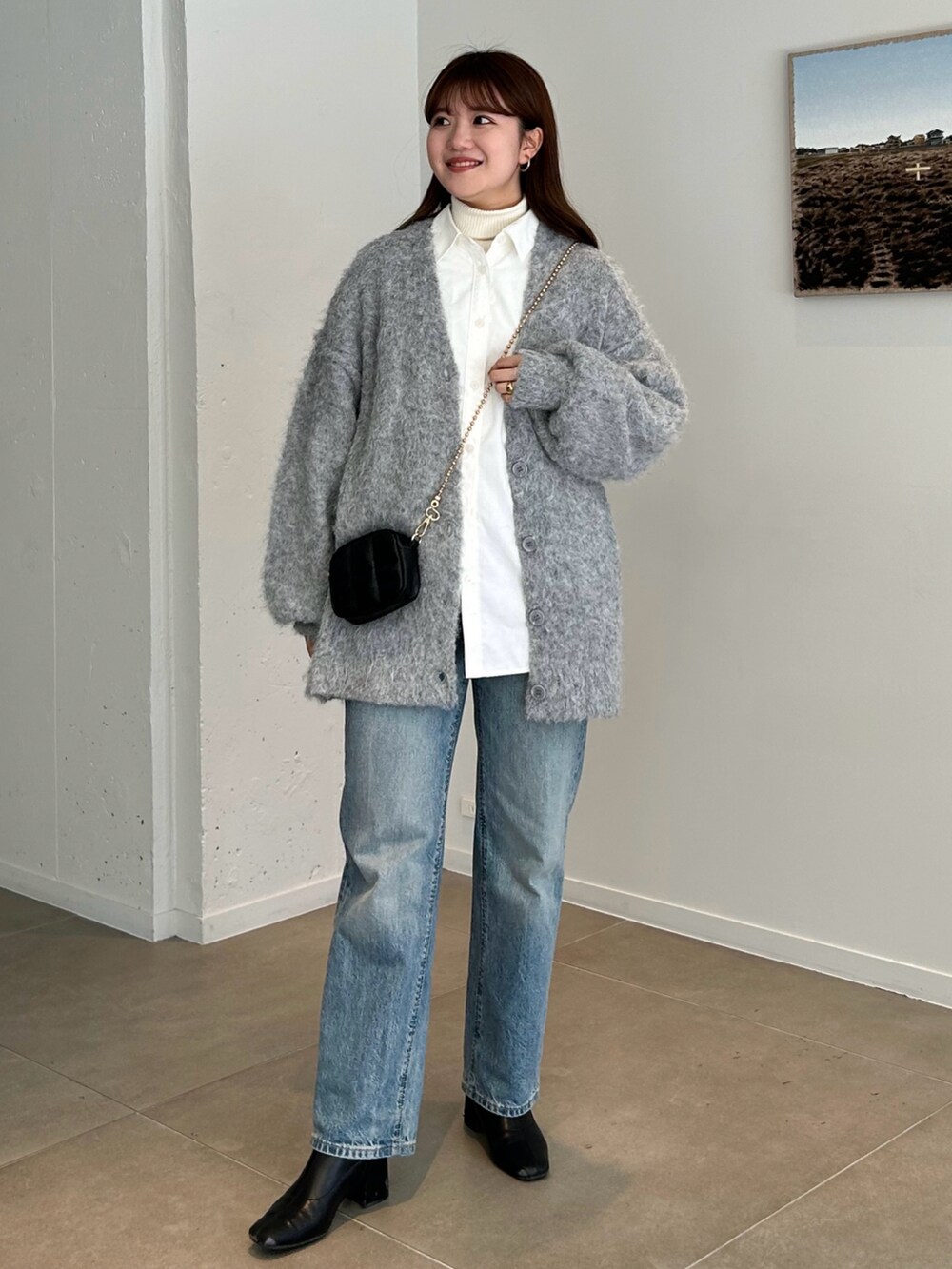 グレー系のカーディガン/ボレロ、ブルー系のデニムパンツ、ブラック系のブーツを着用したレディースの冬コーディネートの2枚目の写真