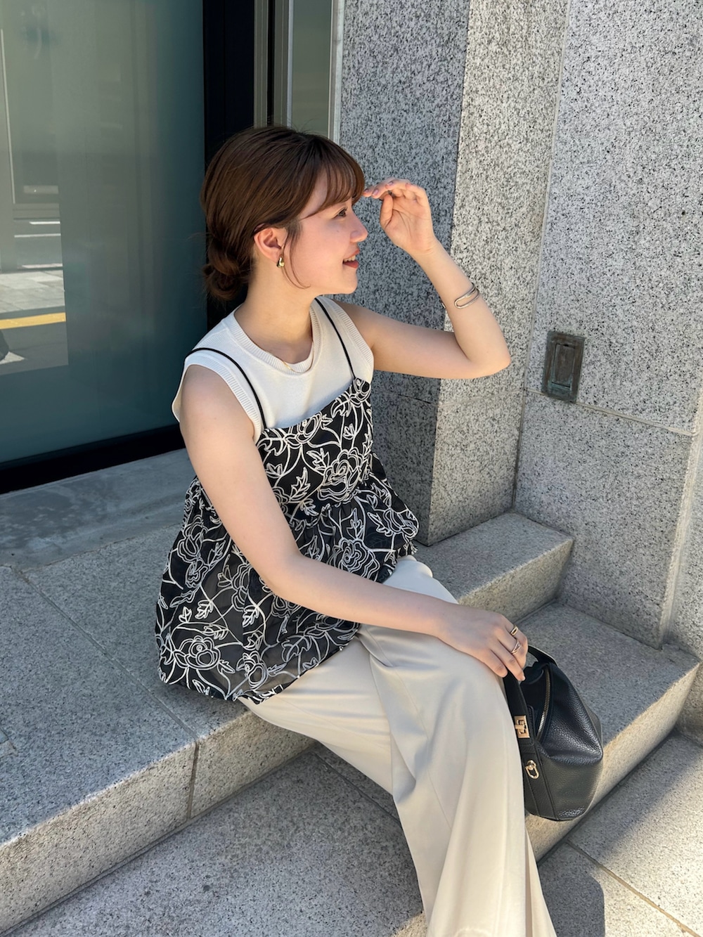 ブラック系のキャミソール、ホワイト系のパンツ、ブラック系のショルダーバッグを着用したレディースの夏コーディネートの2枚目の写真