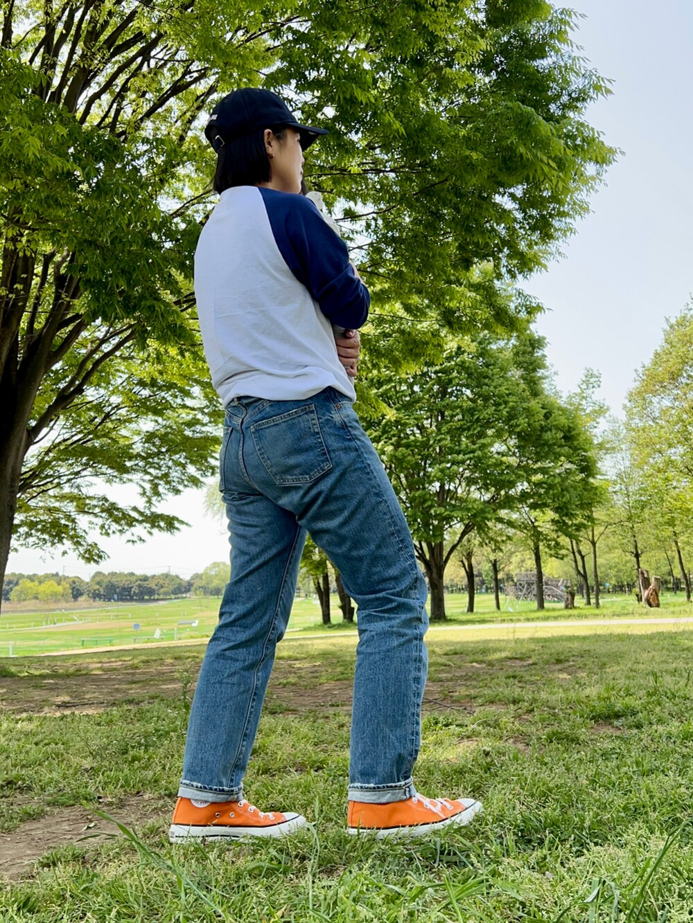 ブルー系のデニムパンツ、オレンジ系のスニーカー、グリーン系のトートバッグを着用したレディースの春コーディネートの2枚目の写真