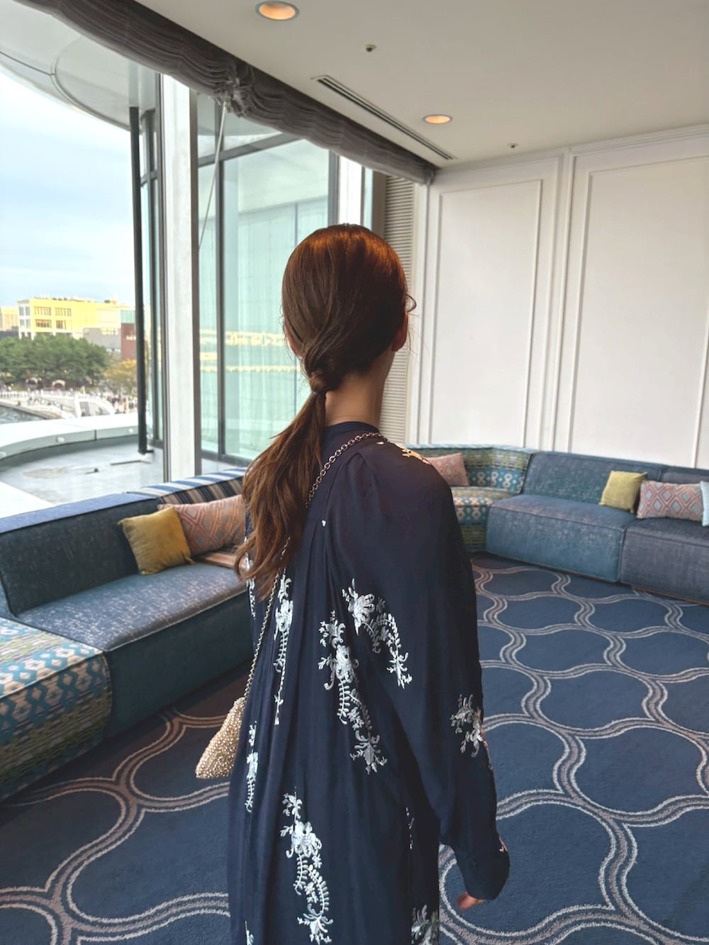 ブルー系のワンピース、ゴールド系のショルダーバッグを着用したレディースの秋コーディネートの2枚目の写真