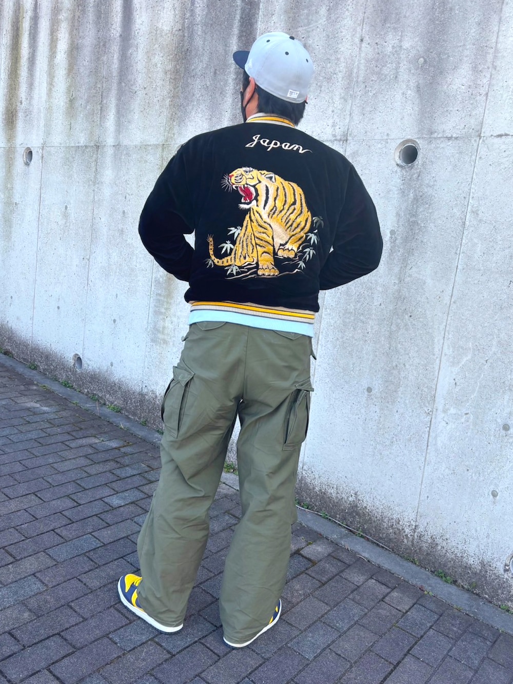 ブルー系のスウェット、ブラック系のスカジャン、グリーン系のカーゴパンツを着用したメンズの春コーディネートの2枚目の写真