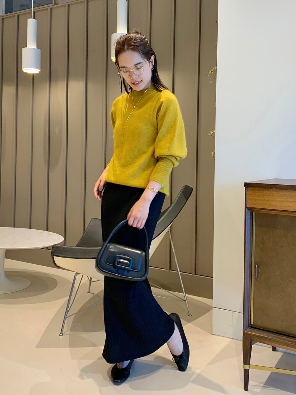 イエロー系のニット/セーター、ブラック系のショルダーバッグ、ブラック系のバレエシューズを着用したレディースの夏コーディネートの2枚目の写真