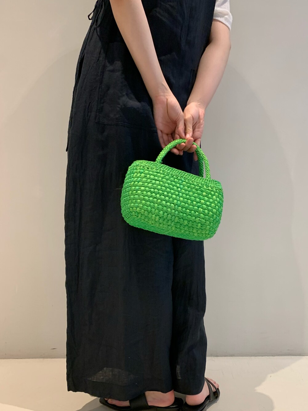 グリーン系のかごバッグ、ブラック系のハットを着用したレディースの春コーディネートの3枚目の写真