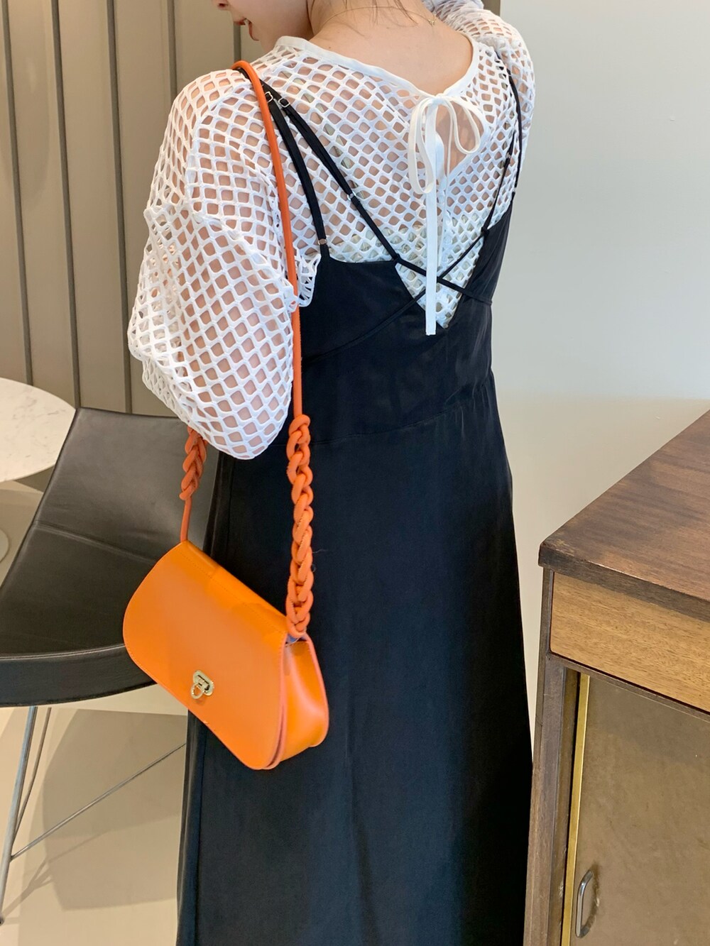 オレンジ系のトートバッグ、ブラック系のワンピース、ホワイト系のTシャツ/カットソーを着用したレディースの春コーディネートの3枚目の写真