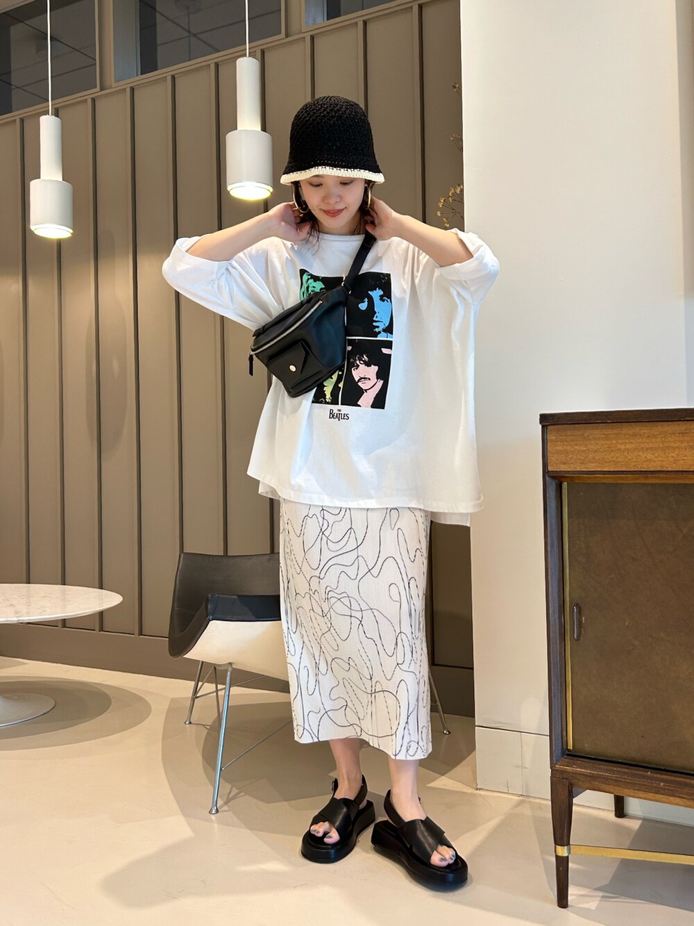 ブラック系のサンダル、ブラック系のボディバッグ/ウエストポーチ、ホワイト系のTシャツ/カットソーを着用したレディースの夏コーディネートの2枚目の写真
