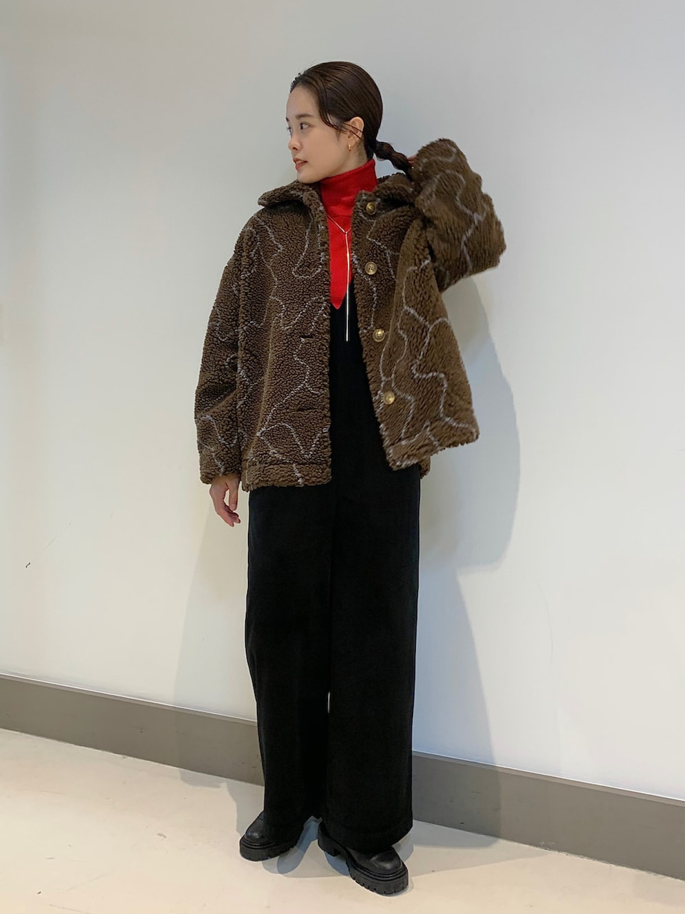 レッド系のニット/セーター、ブラウン系のブルゾン、ブラック系のサロペット/オーバーオールを着用したレディースの秋コーディネートの2枚目の写真