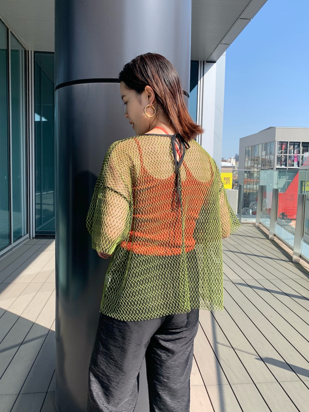 ブラック系のその他パンツ、グリーン系のTシャツ/カットソー、オレンジ系のトートバッグを着用したレディースの春コーディネートの3枚目の写真