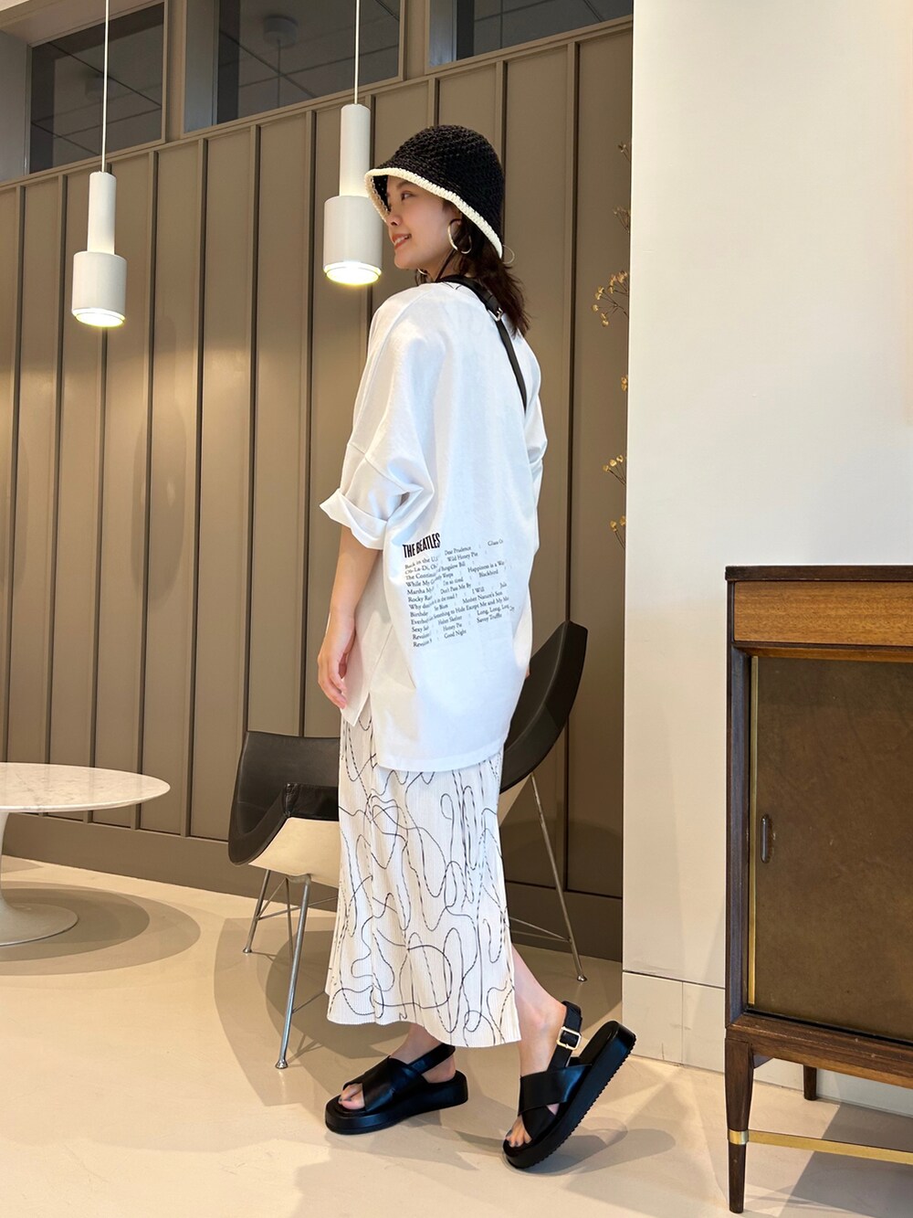 ブラック系のサンダル、ブラック系のボディバッグ/ウエストポーチ、ホワイト系のTシャツ/カットソーを着用したレディースの夏コーディネートの3枚目の写真