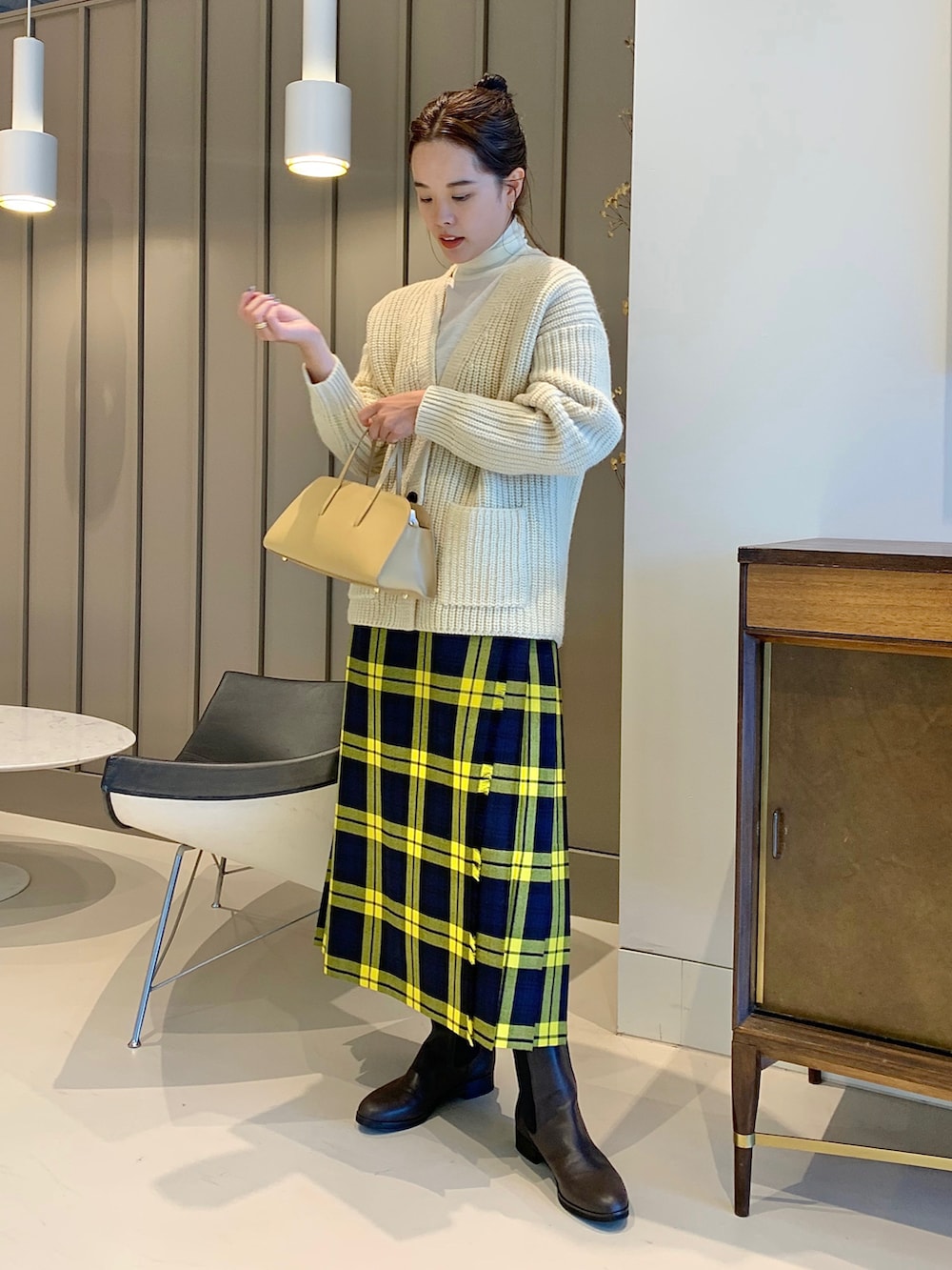 ホワイト系のカーディガン/ボレロ、ホワイト系のニット/セーター、イエロー系のスカートを着用したレディースの夏コーディネートの2枚目の写真