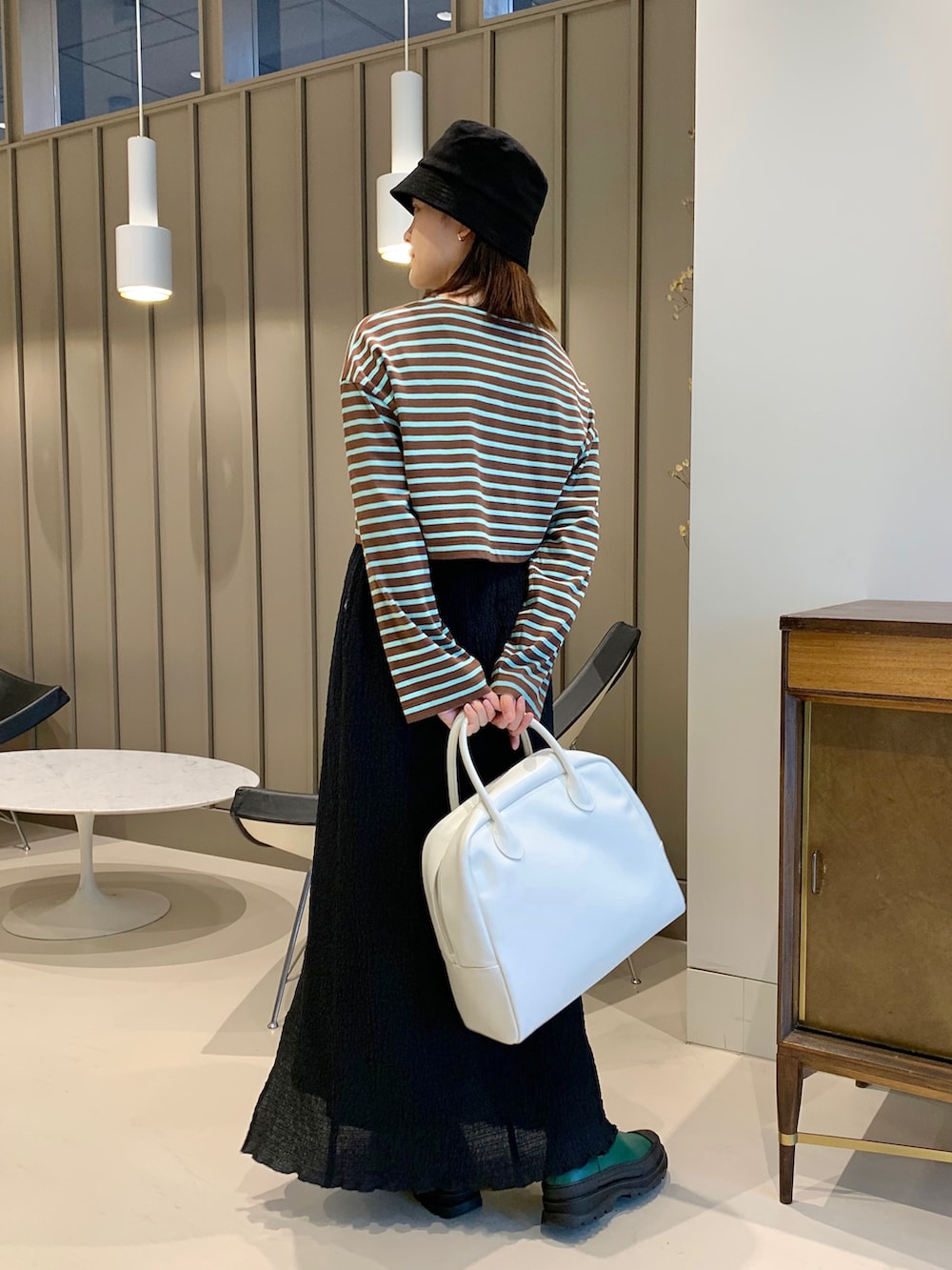 ホワイト系のボストンバッグ、ブラック系のスカート、ブラウン系のTシャツ/カットソーを着用したレディースの夏コーディネートの2枚目の写真