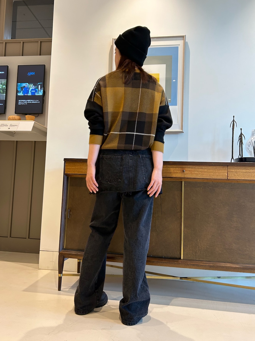 ブラック系のデニムパンツ、ブラウン系のニット/セーター、ブラック系のニットキャップ/ビーニーを着用したレディースの夏コーディネートの3枚目の写真