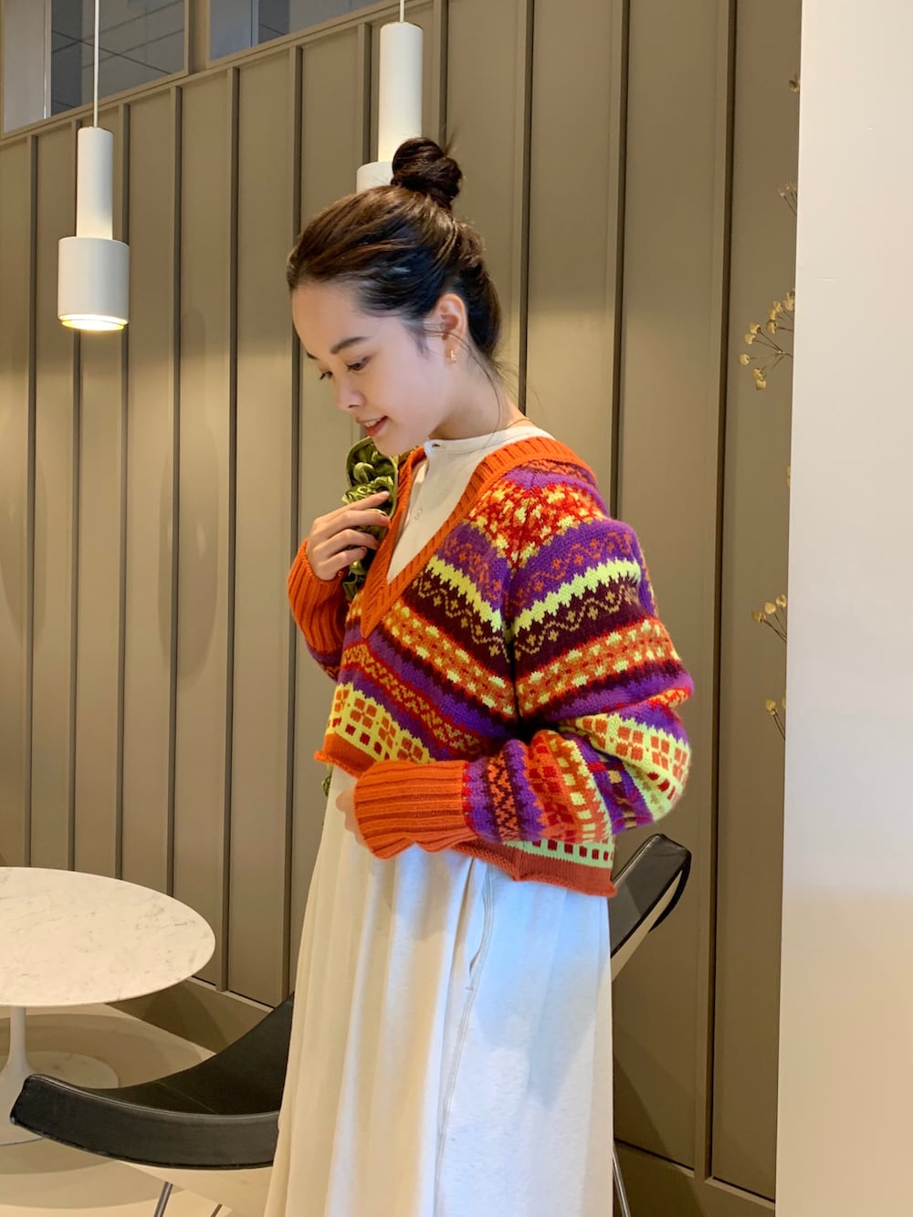 オレンジ系のニット/セーター、ベージュ系のワンピース、グリーン系のスラックスを着用したレディースの秋コーディネートの2枚目の写真