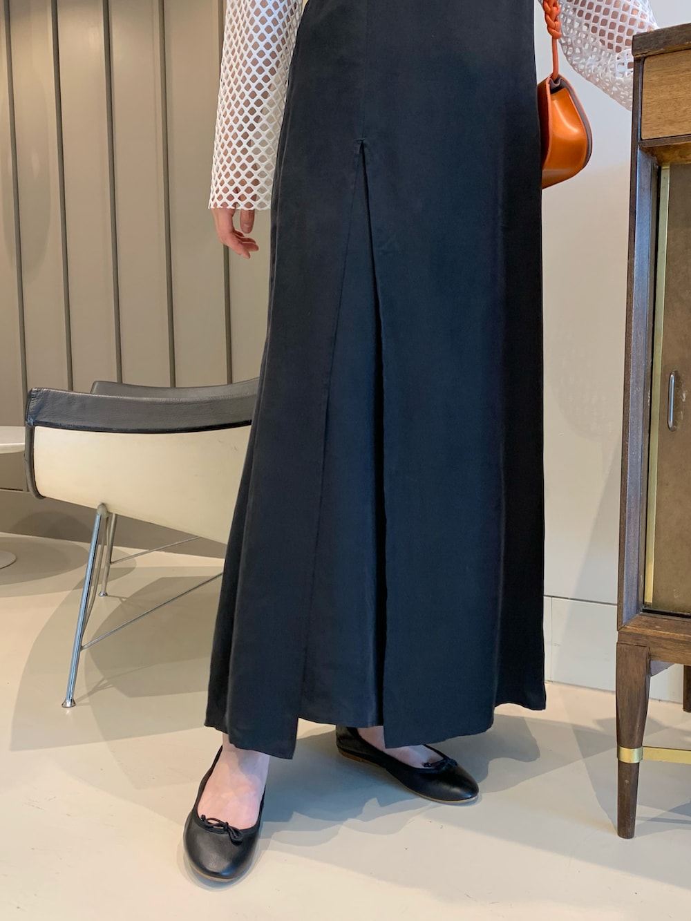 オレンジ系のトートバッグ、ブラック系のワンピース、ホワイト系のTシャツ/カットソーを着用したレディースの春コーディネートの4枚目の写真