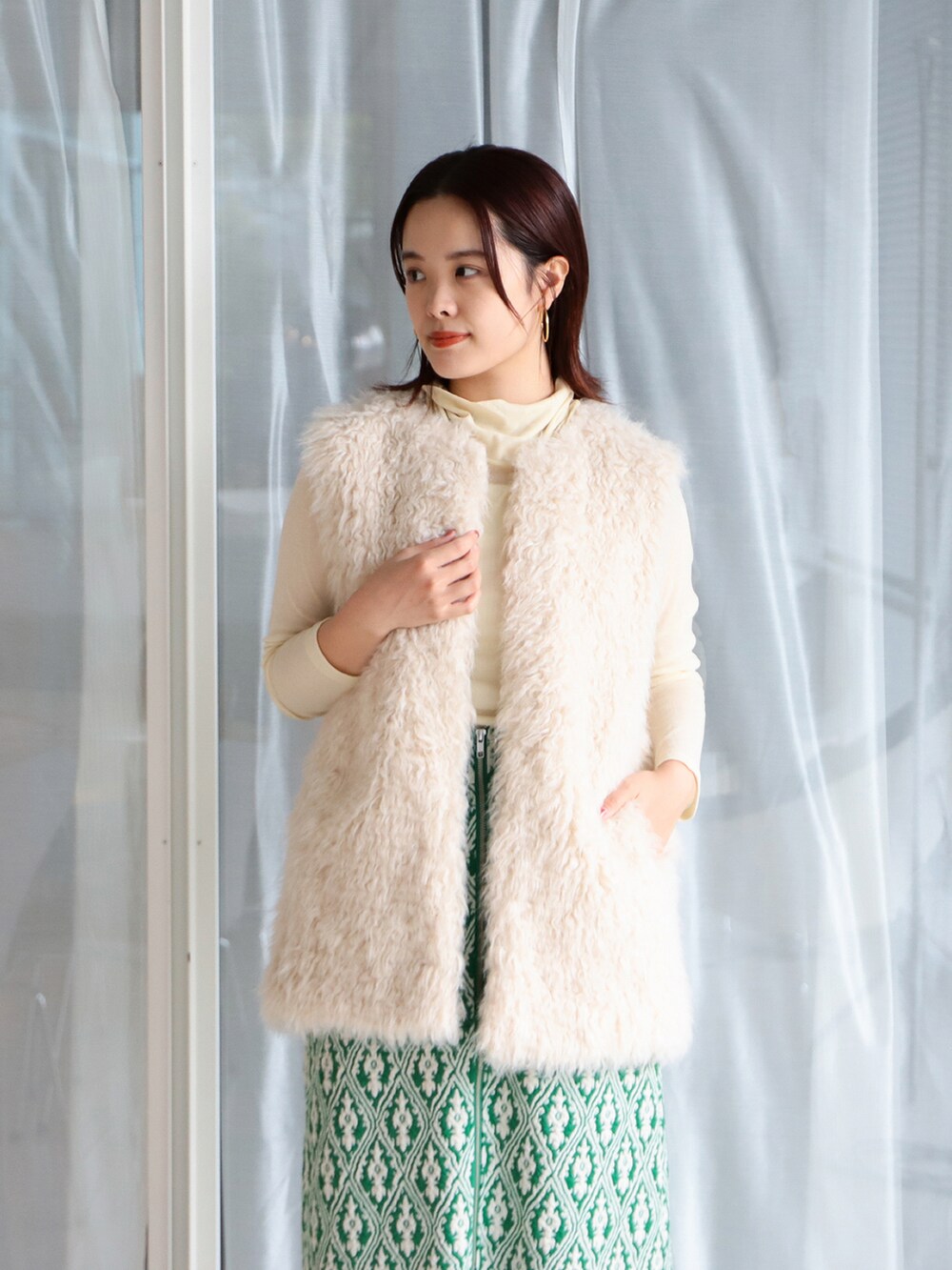 ブラック系のハンドバッグ、ホワイト系のベスト、ベージュ系のTシャツ/カットソーを着用したレディースの夏コーディネートの3枚目の写真