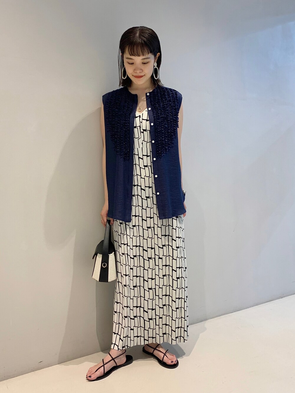 ホワイト系のワンピース、ブルー系のシャツ/ブラウス、ブラック系のトートバッグを着用したレディースの春コーディネートの2枚目の写真