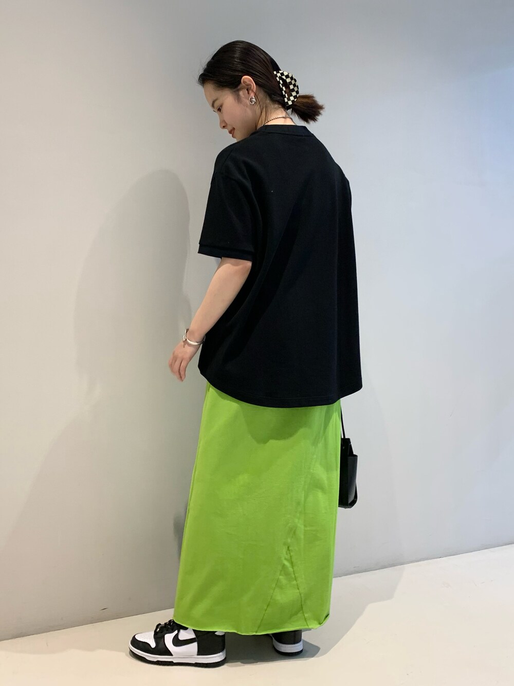 ブラック系のTシャツ/カットソー、グリーン系のスカート、ブラック系のトートバッグを着用したレディースの春コーディネートの2枚目の写真