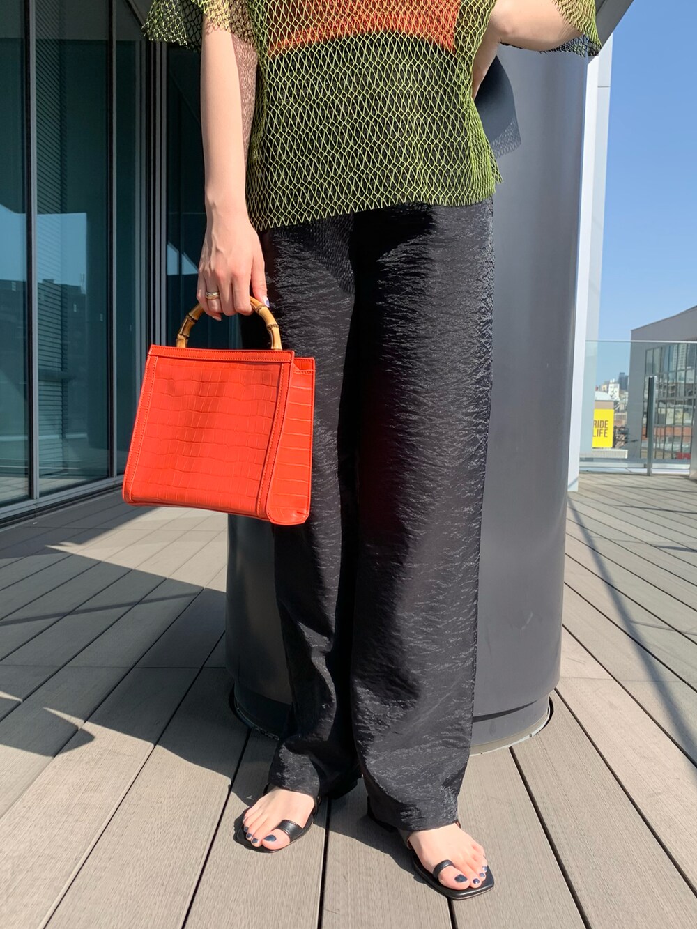 ブラック系のその他パンツ、グリーン系のTシャツ/カットソー、オレンジ系のトートバッグを着用したレディースの春コーディネートの4枚目の写真