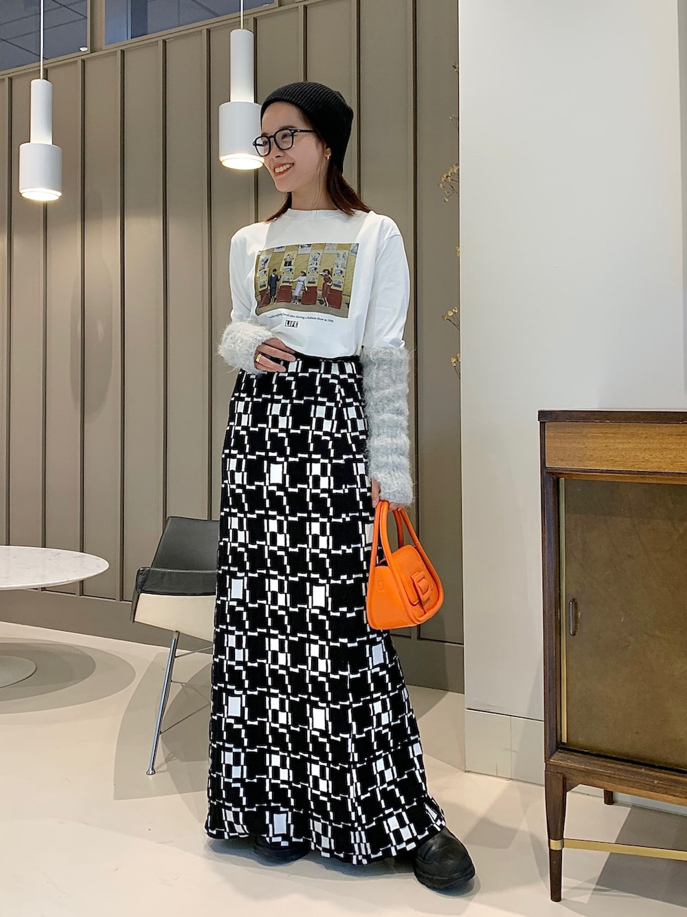 オレンジ系のショルダーバッグ、ホワイト系のTシャツ/カットソー、ブラック系のスカートを着用したレディースの夏コーディネートの2枚目の写真