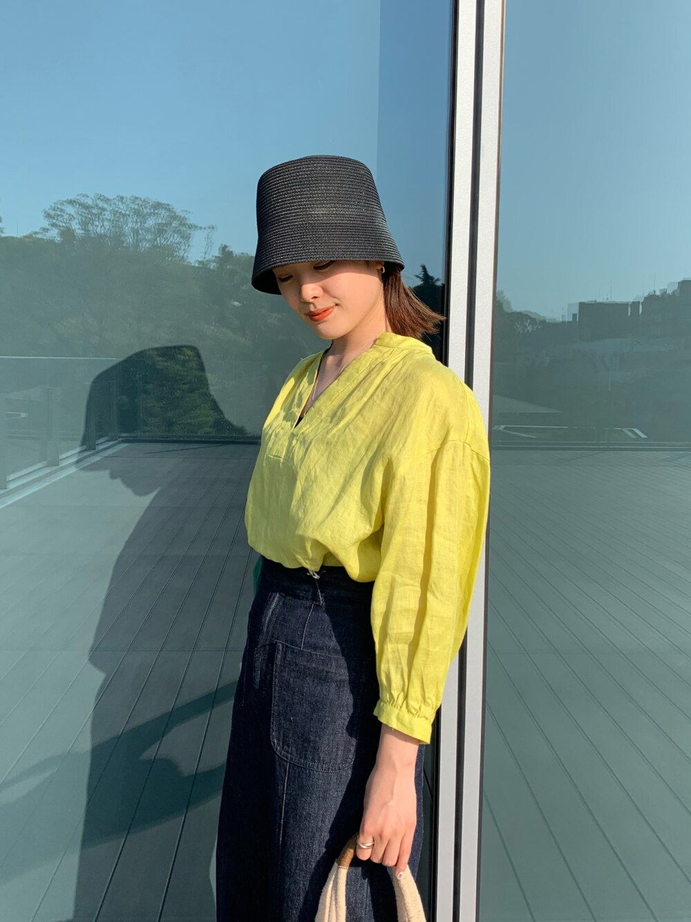 イエロー系のシャツ/ブラウス、ブラウン系のかごバッグ、ブラック系のその他シューズを着用したレディースの春コーディネートの2枚目の写真