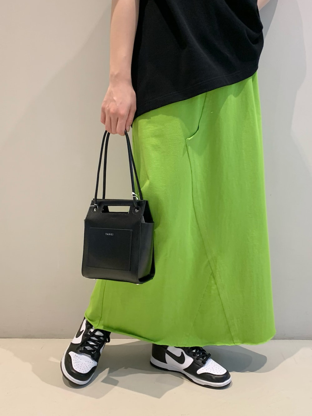 ブラック系のTシャツ/カットソー、グリーン系のスカート、ブラック系のトートバッグを着用したレディースの春コーディネートの3枚目の写真