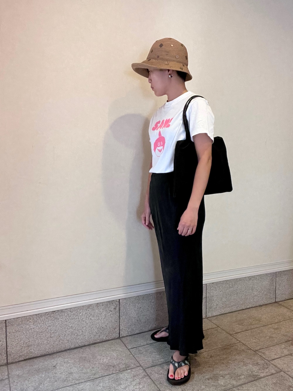 ホワイト系のTシャツ/カットソー、グレー系のスカート、ブラック系のトートバッグを着用したレディースの夏コーディネートの3枚目の写真