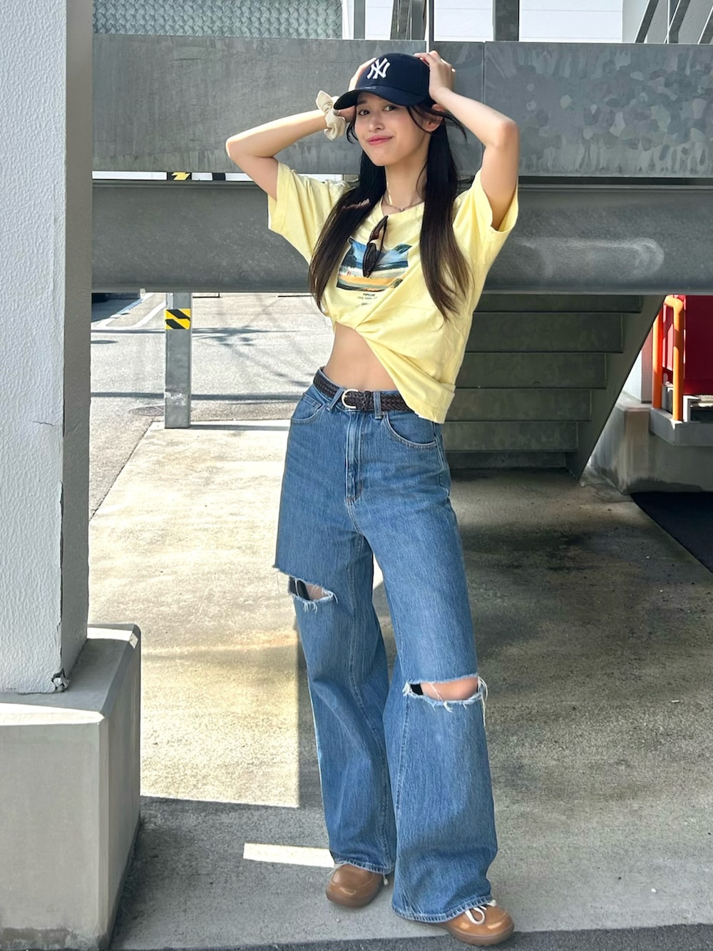 イエロー系のTシャツ/カットソー、ブルー系のデニムパンツ、ブラウン系のスニーカーを着用したレディースの夏コーディネートの2枚目の写真