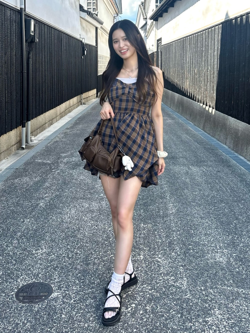 ブルー系のワンピース、ブラック系のデニムパンツ、ホワイト系のキャミソールを着用したレディースの夏コーディネートの2枚目の写真