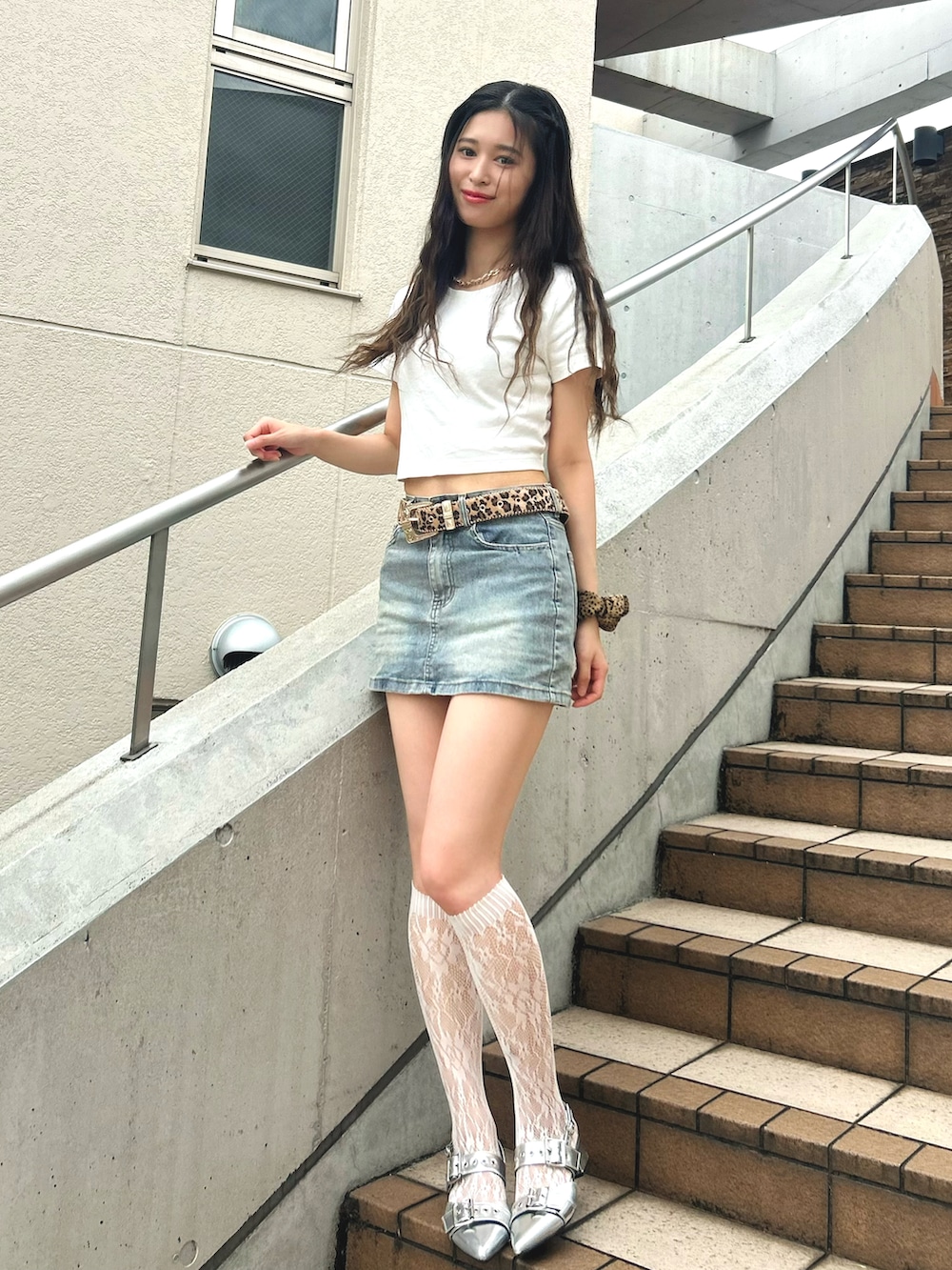 シルバー系のパンプス、ホワイト系のTシャツ/カットソー、ブルー系のデニムスカートを着用したレディースの夏コーディネートの2枚目の写真
