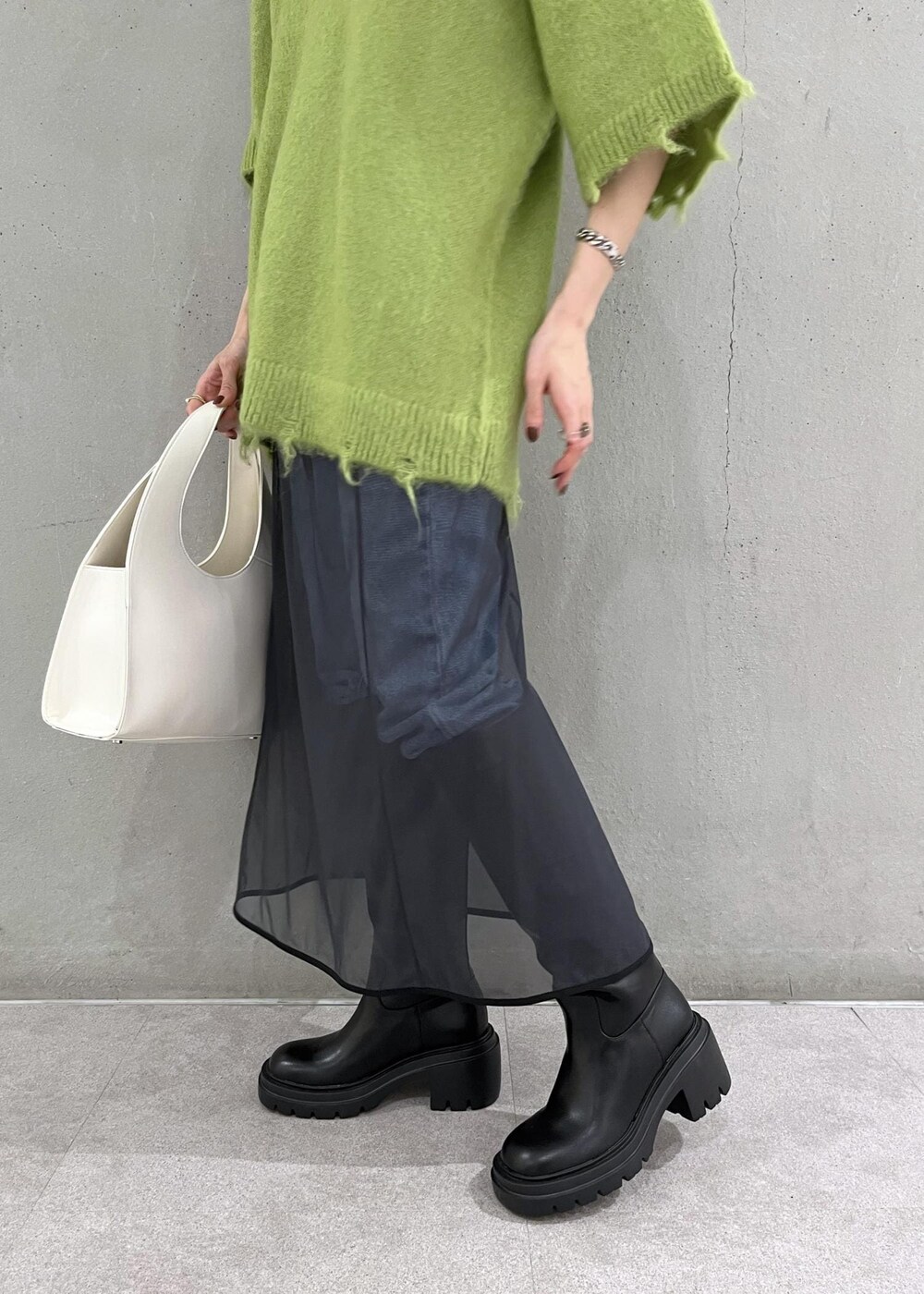 ブラック系のブーツ、ホワイト系のハンドバッグ、ブルー系のデニムパンツを着用したレディースの秋コーディネートの6枚目の写真