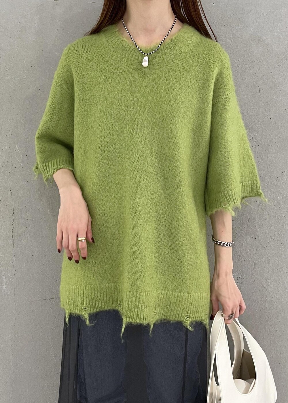 ブラック系のブーツ、ホワイト系のハンドバッグ、ブルー系のデニムパンツを着用したレディースの秋コーディネートの5枚目の写真