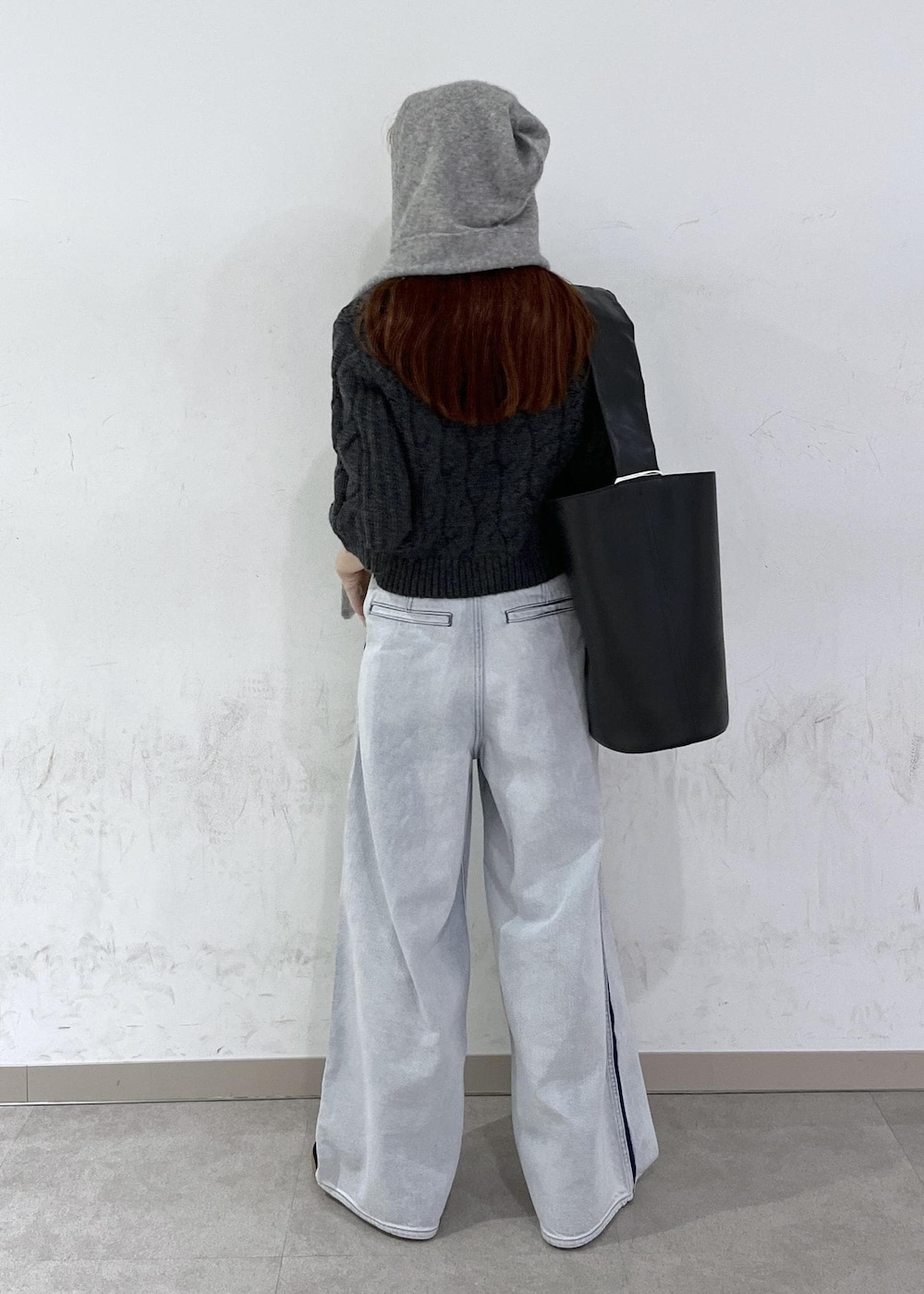 ブルー系のデニムパンツ、ブラック系のショルダーバッグ、グレー系のニット/セーターを着用したレディースの秋コーディネートの4枚目の写真