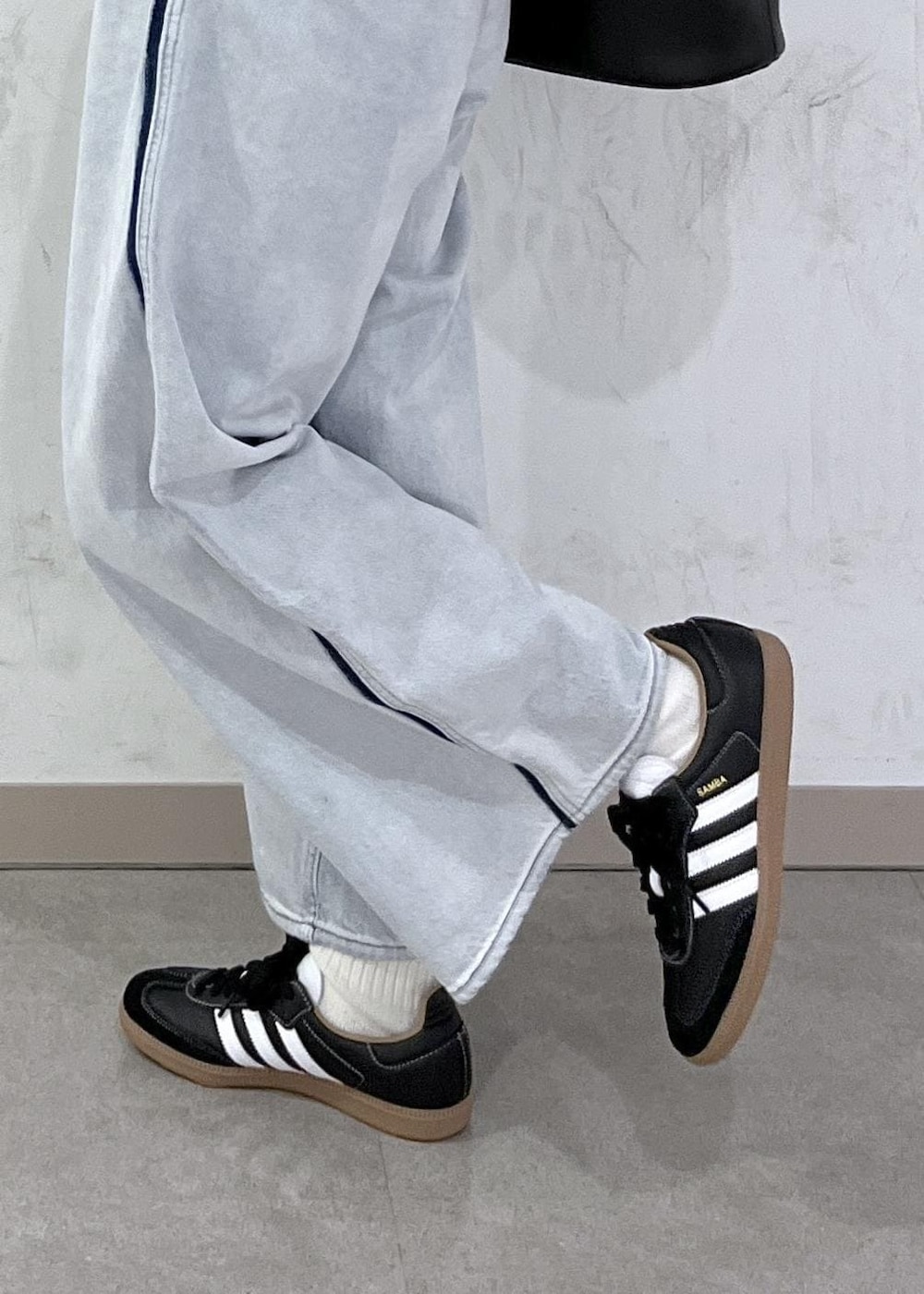 ブルー系のデニムパンツ、ブラック系のショルダーバッグ、グレー系のニット/セーターを着用したレディースの秋コーディネートの5枚目の写真