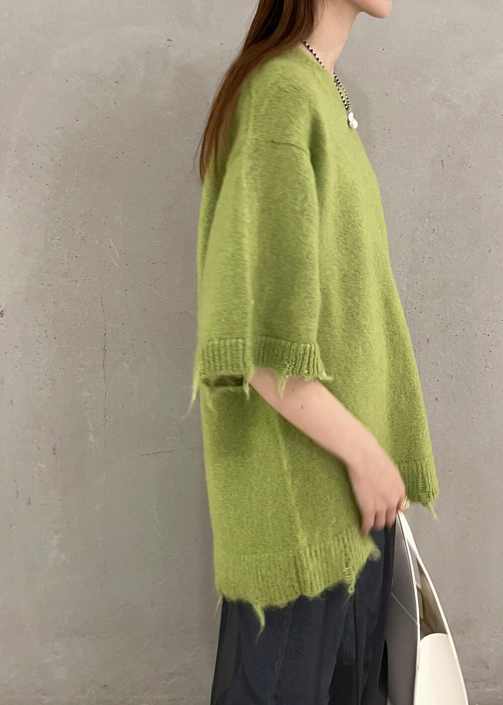 ブラック系のブーツ、ホワイト系のハンドバッグ、ブルー系のデニムパンツを着用したレディースの秋コーディネートの4枚目の写真