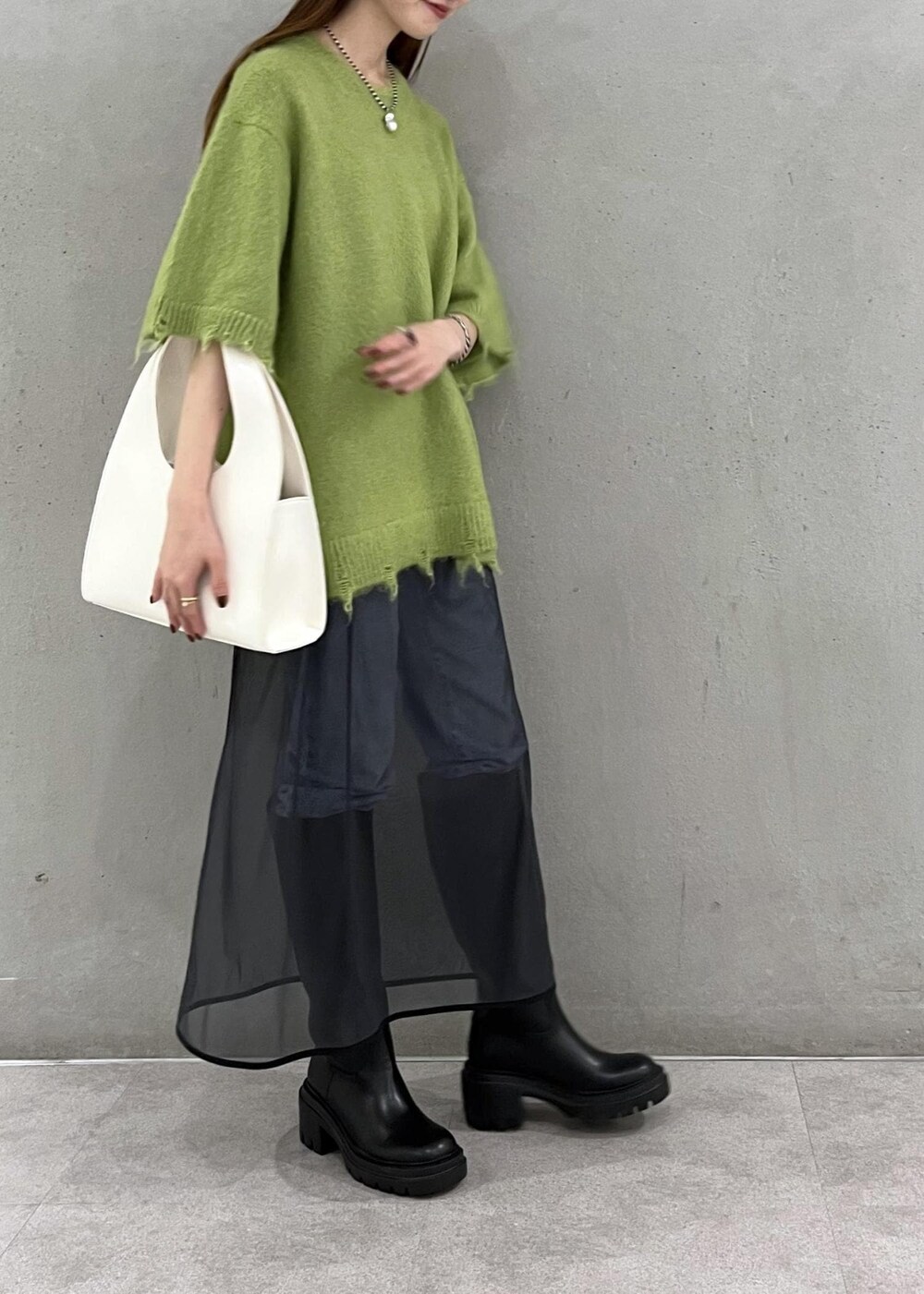 ブラック系のブーツ、ホワイト系のハンドバッグ、ブルー系のデニムパンツを着用したレディースの秋コーディネートの2枚目の写真