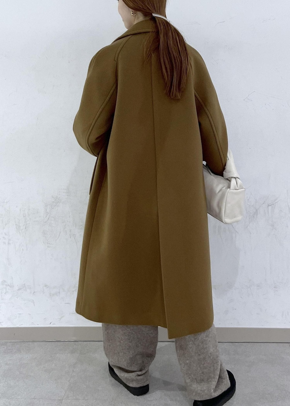 ホワイト系のハンドバッグ、イエロー系のステンカラーコート、ベージュ系のニット/セーターを着用したレディースの秋コーディネートの4枚目の写真