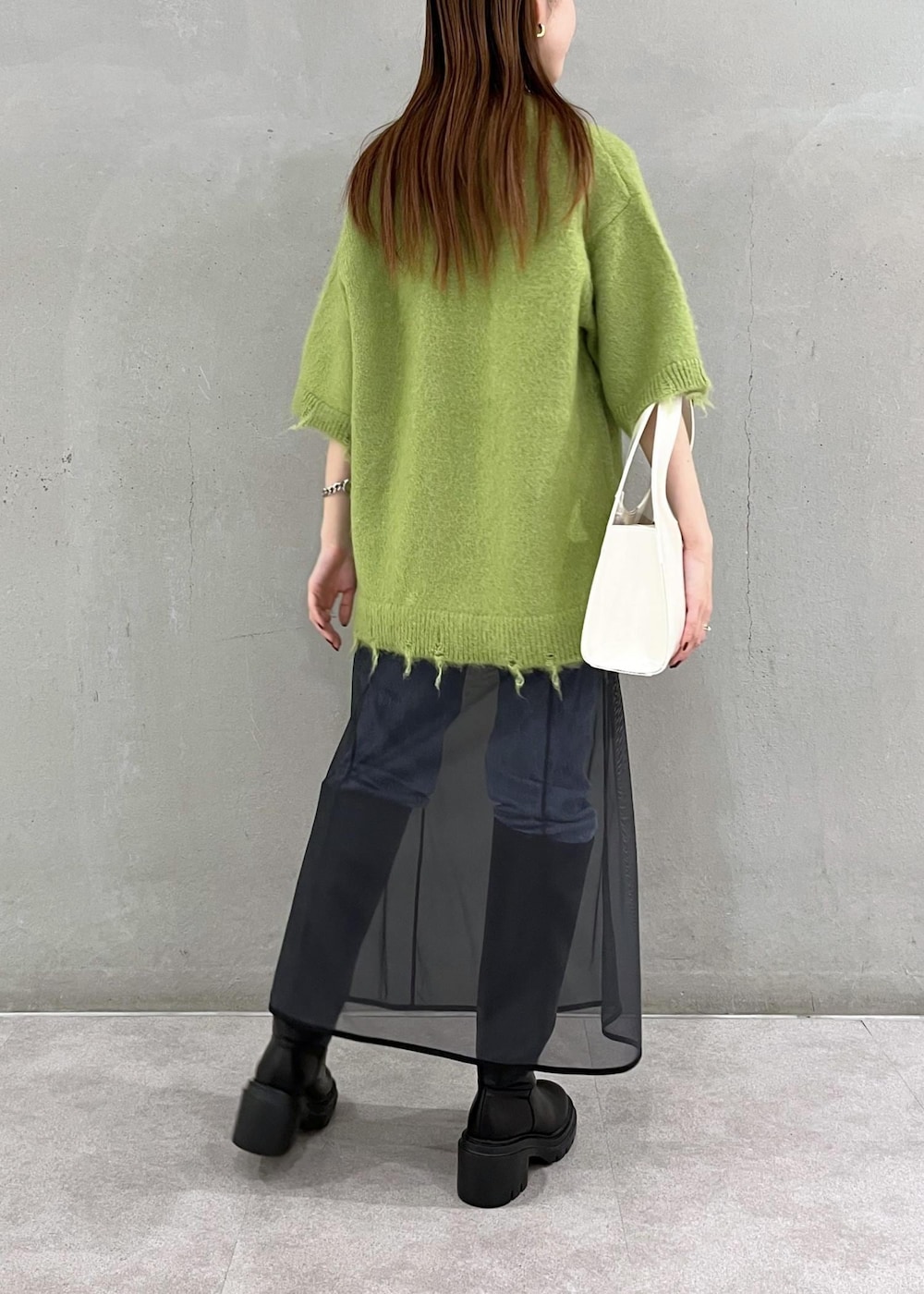 ブラック系のブーツ、ホワイト系のハンドバッグ、ブルー系のデニムパンツを着用したレディースの秋コーディネートの3枚目の写真