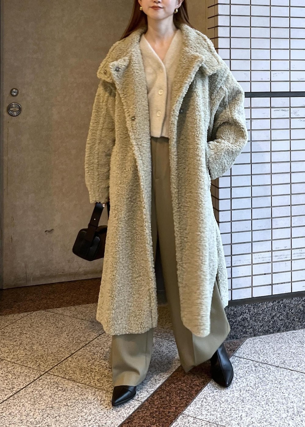 ブラック系のブーツ、ホワイト系のカーディガン/ボレロ、グリーン系のその他アウターを着用したレディースの冬コーディネートの3枚目の写真