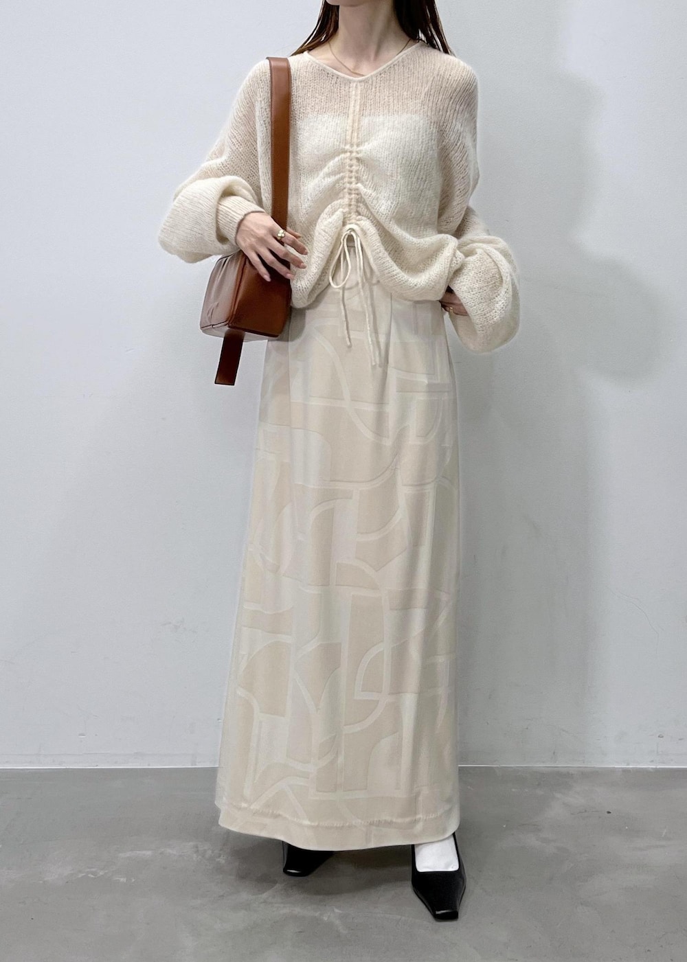 ホワイト系のスカート、ベージュ系のニット/セーター、ブラウン系のショルダーバッグを着用したレディースの夏コーディネートの2枚目の写真